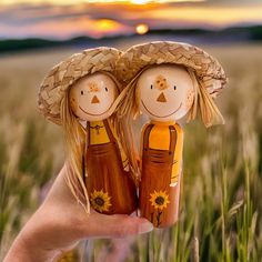 two wooden dolls holding each other in the middle of a wheat field at sunset or dawn