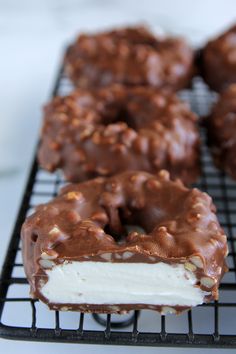 chocolate covered doughnuts on a cooling rack with white frosting and sprinkles