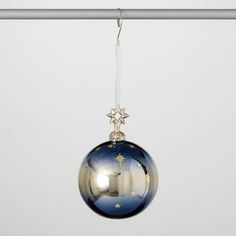 a glass ball ornament hanging from a metal rod with a white background and stars on it