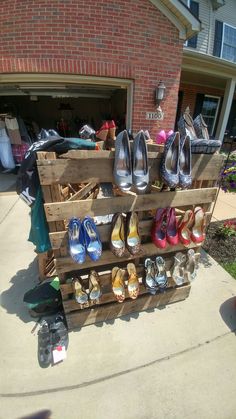 several pairs of shoes are on display in front of a brick building with an open garage door