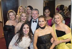 a group of people standing next to each other in front of a mirror at a formal event