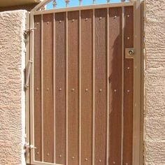 an open wooden gate on the side of a building with metal bars and rivets