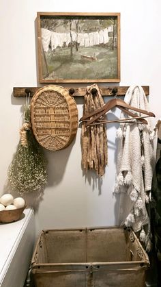 an old basket is hanging on the wall next to a painting and other items in a room