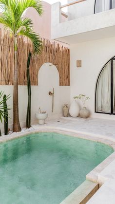 an outdoor swimming pool surrounded by palm trees and wicker fenced in to the building