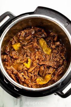 a pot filled with meat and peppers on top of a table