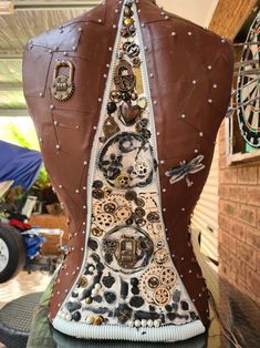 the back of a woman's brown leather jacket with buttons and chains on it