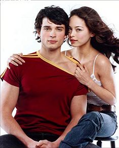 a man sitting next to a woman on top of a stool in front of a white background