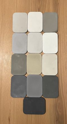 several different shades of gray and white tile on a wooden surface, arranged in the shape of a square