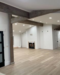 an empty living room with wood floors and white walls, exposed beams in the ceiling