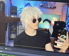 a man with white hair and black sunglasses is looking at his cell phone in front of him