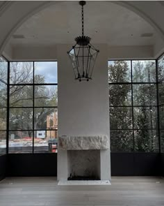 an empty room with large windows and a chandelier hanging from it's ceiling