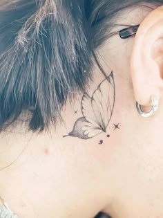 a woman with a butterfly tattoo on her behind the ear is looking down at something