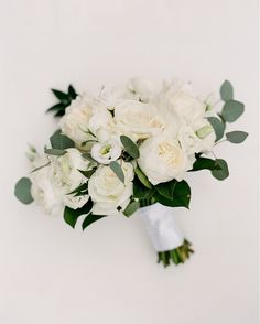 a bridal bouquet with white flowers and greenery