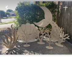 several wooden sculptures sitting on the ground in front of a tree and fenced area