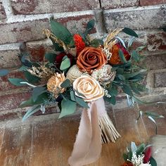 a bridal bouquet sitting on top of a wooden floor next to a brick wall