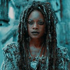 a woman with dreadlocks and makeup looks at the camera