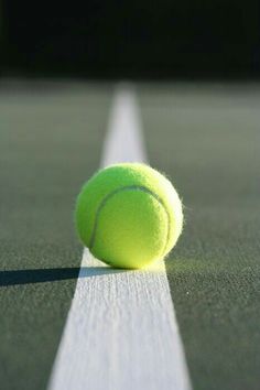 a tennis ball sitting on top of a tennis court with the line in front of it