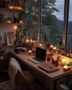 a laptop computer sitting on top of a wooden desk in front of a window filled with candles