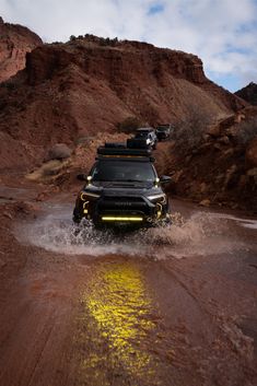 the jeep is driving through some water in the desert, with mountains in the background