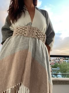 a woman standing on top of a balcony next to a building wearing a shawl