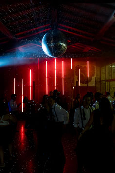 a group of people standing in a room with red and blue lights on the ceiling