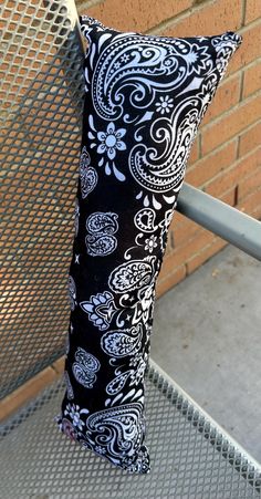 a black and white pillow sitting on top of a metal bench next to a brick wall