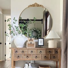 a mirror on the wall above a wooden dresser with drawers and books in front of it