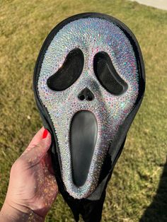 someone is holding up a mask that looks like a scream face with glitter on it