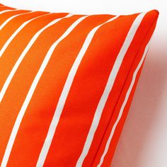 an orange and white striped pillow sitting on top of a bed