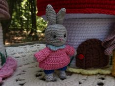 there are crocheted toys that look like rabbits on the bed, and one is wearing a pink dress