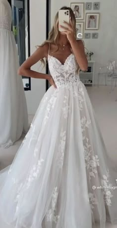 a woman taking a selfie while wearing a wedding dress in front of a mirror