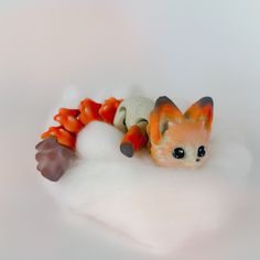 a toy cat laying on top of a pile of snow