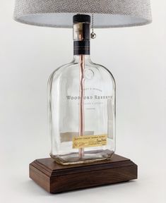 a glass bottle sitting on top of a wooden base next to a lampshade