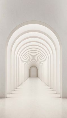 an empty tunnel with white walls and arches leading to the light at the end is seen in this image