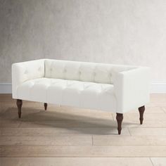 a white couch sitting on top of a hard wood floor next to a gray wall