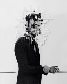 a man sitting in front of a wall with multiple pieces of paper on it's face