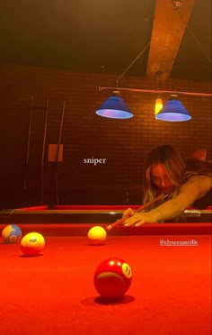 a woman leaning over a pool table to pick up balls