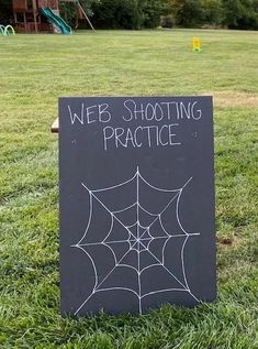 a sign that says web shooting practice in front of a playground with a spiderweb on it