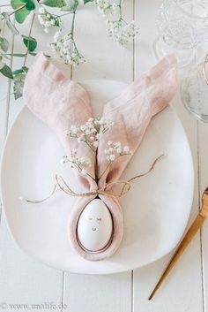 a white plate topped with a pink napkin and an egg shell on top of it