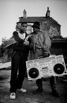 two men standing next to each other near a boom box