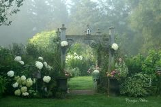 a garden with white flowers and greenery on either side of the entrance to it