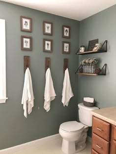 a bathroom with towels hanging on the wall and pictures on the wall above the toilet