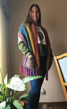 a woman standing next to a potted plant wearing a multicolored shawl