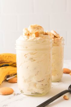 two jars filled with food sitting on top of a table next to bananas and spoons