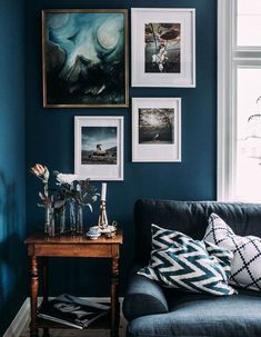 a living room with blue walls and pictures hanging on the wall, including flowers in vases