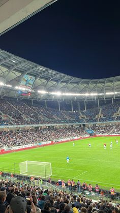 a soccer stadium filled with people watching a game on the field and in the stands