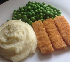 a white plate topped with mashed potatoes and green peas