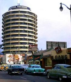 cars are driving down the street in front of a tall building