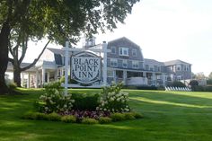 the black point inn sign in front of some trees and lawn with chairs around it