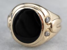 This Retro Era men's ring makes a bold statement! The black onyx gleams beautifully and creates a striking contrast against the bright polish of the 14 karat gold mounting. Diamond accents inject sparkle and light into this masculine design. Metal: 14K Yellow Gold Gem: Black Onyx Gem Measurements: 11.4 x 13.6 mm, Oval Accents: 4 Diamonds totaling .20 Carats, SI2 in Clarity, I in Color Ring Size: 8.50 Marks: "14K" Stamped on the inside band Diamond Gold Ring, Retro Era, Masculine Design, Cameo Ring, Gold Gift, Diamond Gold, Onyx Ring, Men's Ring, Color Ring